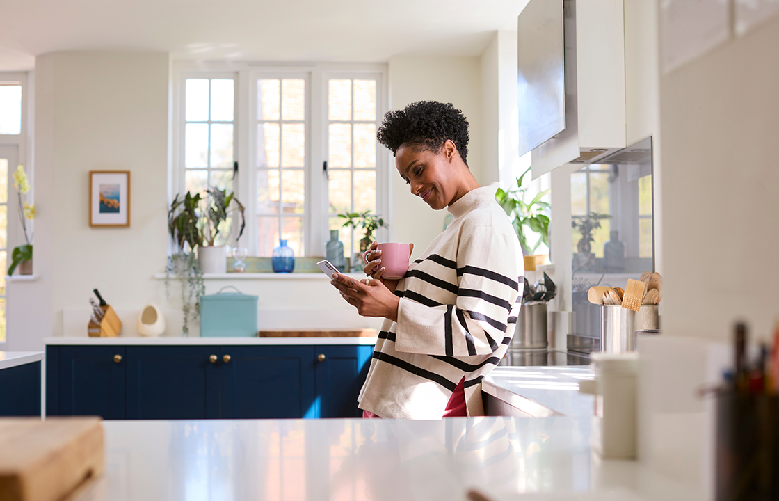 woman looking at her phone while drinking coffee