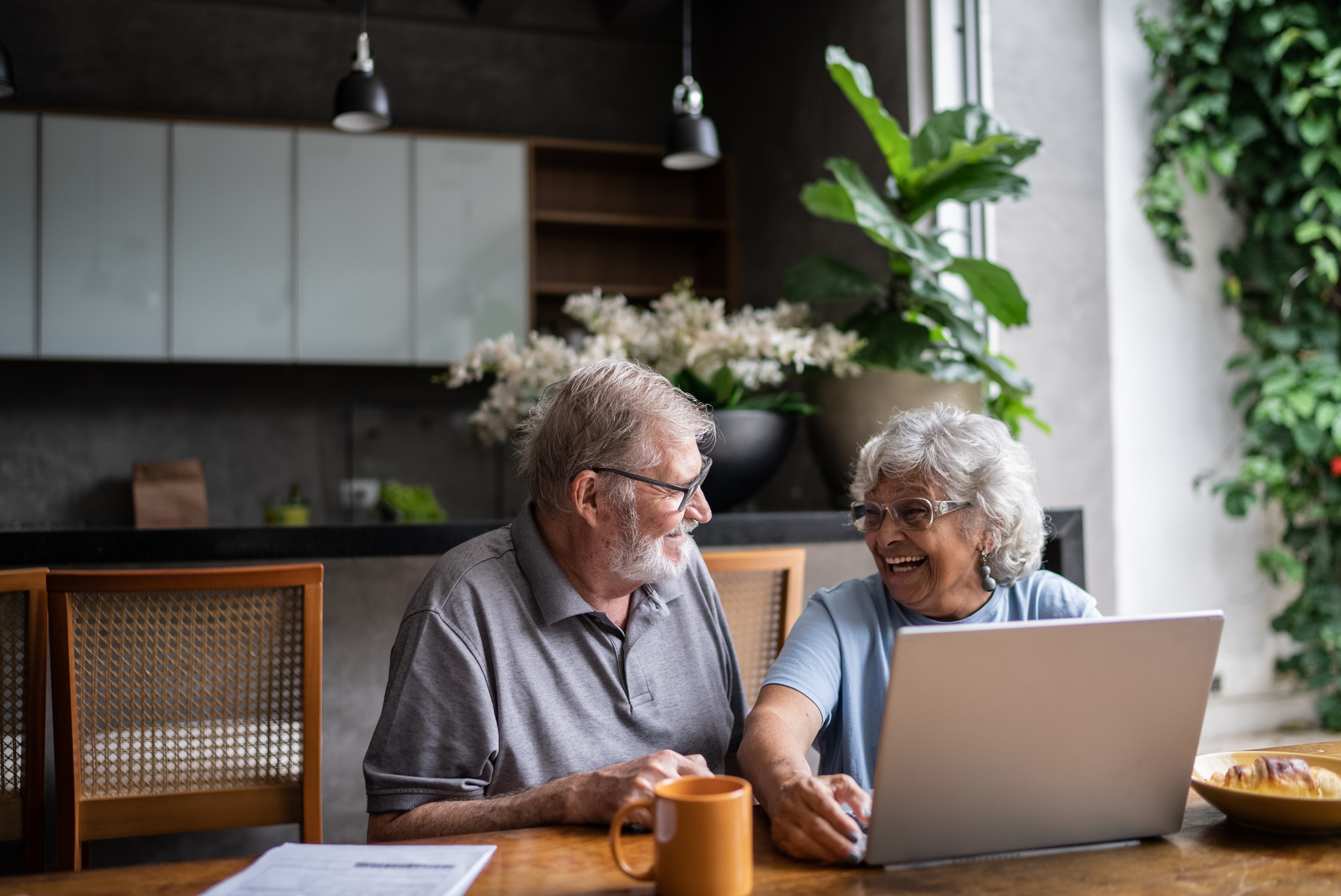 Happy older couple in front of laptop in their home